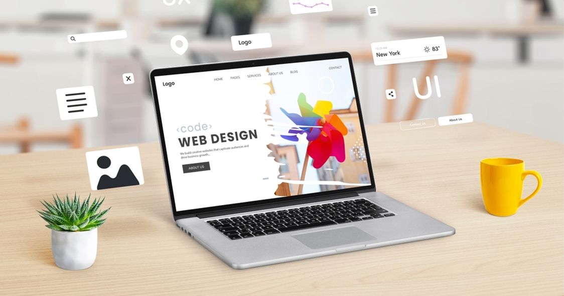 A laptop on a desk showing a web design layout with floating UI and UX elements.